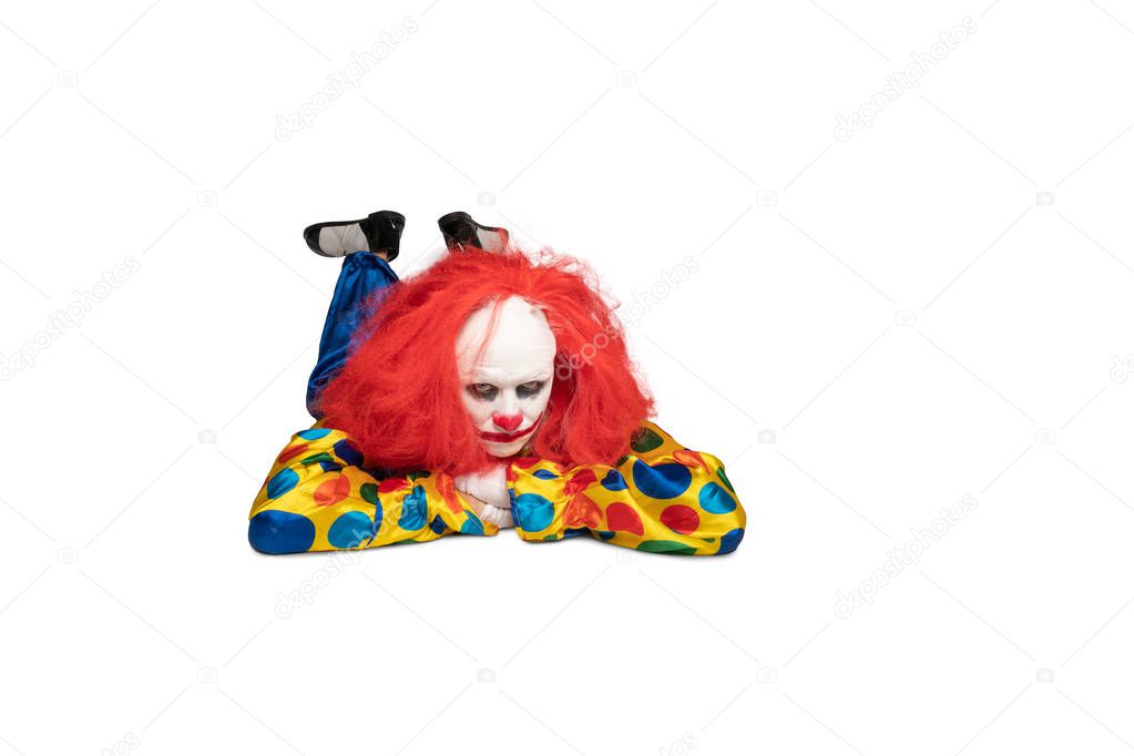 A bored clown lies on the floor and looks at the camera