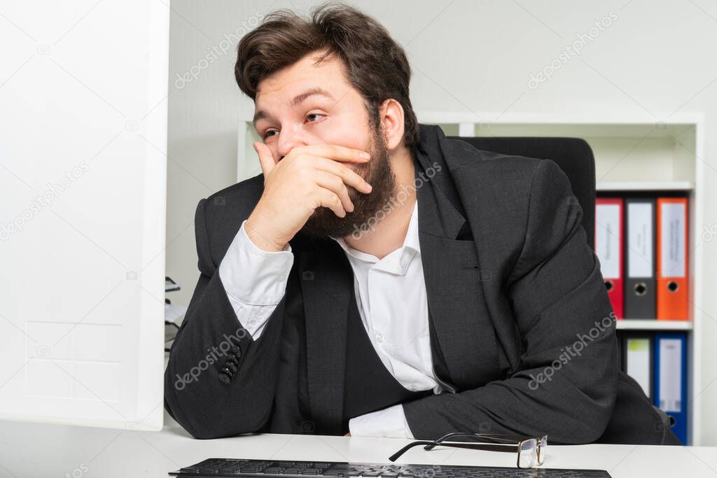 An over-worked businessman in the office stares at the monitor