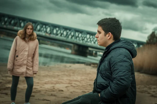 Doğada kız arkadaşıyla oturan dalgın bir gencin yakın çekimi.