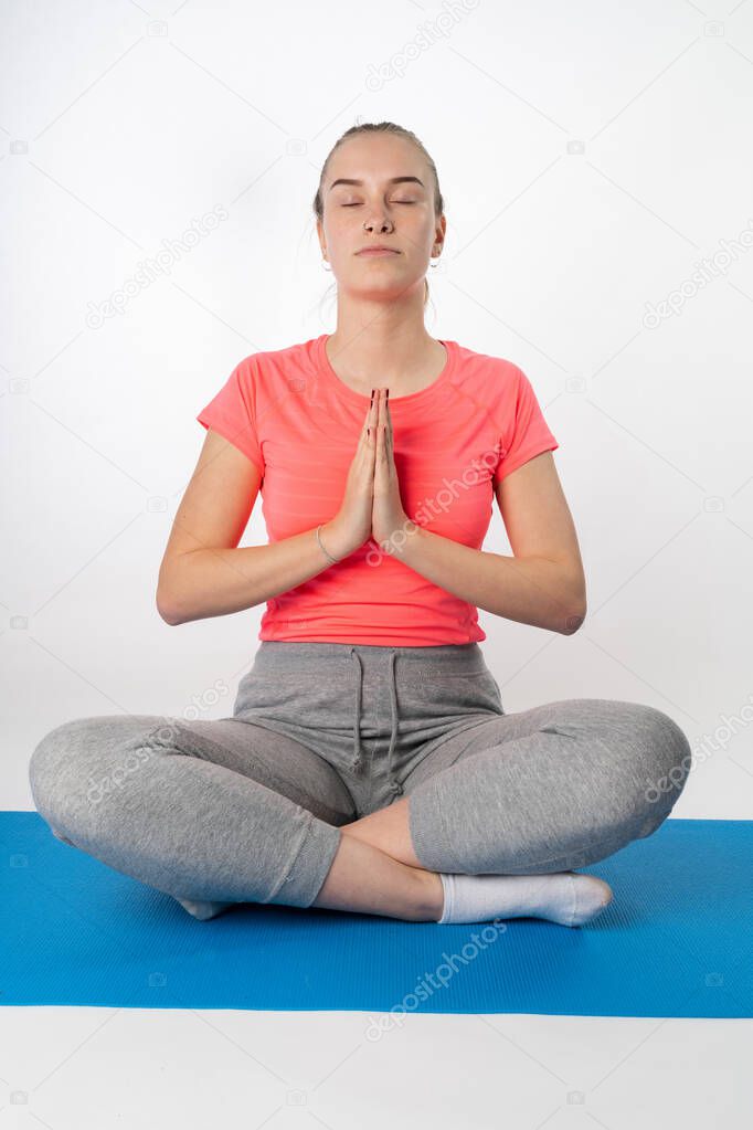 young woman does a yoga exercise on a yoga mat