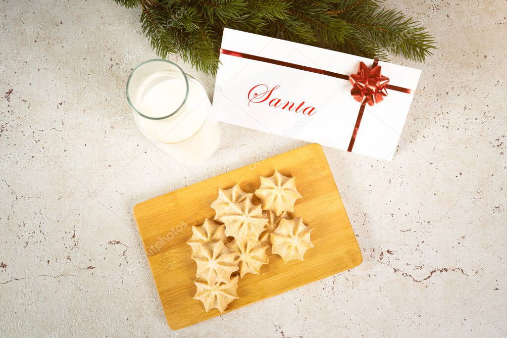 Milk and biscuits for santa with an envelope on a table view from the top