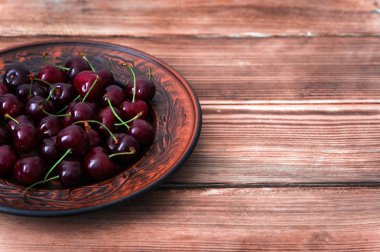 Ahşap rustik arka plan metin yazabileceğiniz boş bir kopya ile tabağa taze kırmızı kiraz meyve