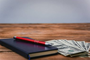 Dolar, defter ve kalem ahşap arka plan üzerinde. İş Tema