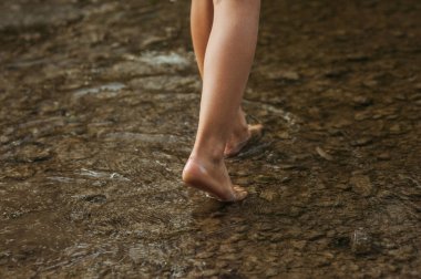 Suyun içinde çocuğun bacaklarının yatay görüntüsü. Göl kenarında yalınayak yürümek, göl kenarında su birikintisi. Metin için alanı kopyala
