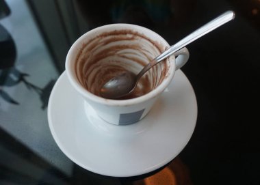 Bir otelde bir cam masa üzerinde bir kaşıkla boş kahve fincanı