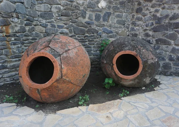 Two Empty Georgian Wine Jars in Front of a Stone Wall