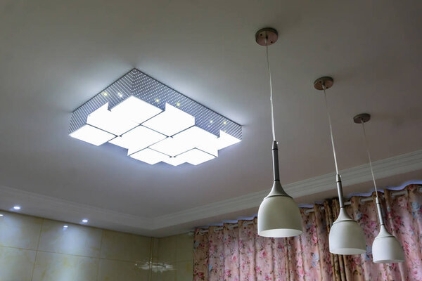 Четырехугольная прямоугольная люстра с тремя внутренними потолками включена
