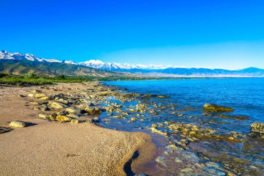 Tian Shan dağ silsilesi Issyk Kul göl kıyısı taş taş Sandy Beach kar ile şapkalı