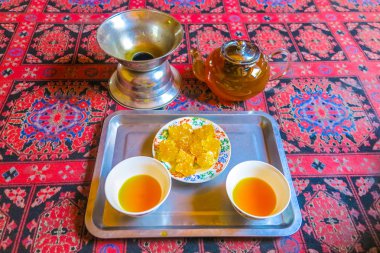 Kaşgar çay evi iki bardak halı üzerinde sarı renkli çay dolu