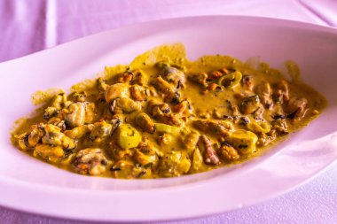 Yunan geleneksel midye Midia Saganaki yeşil biber bir Oval beyaz tabağa dilimlenmiş.