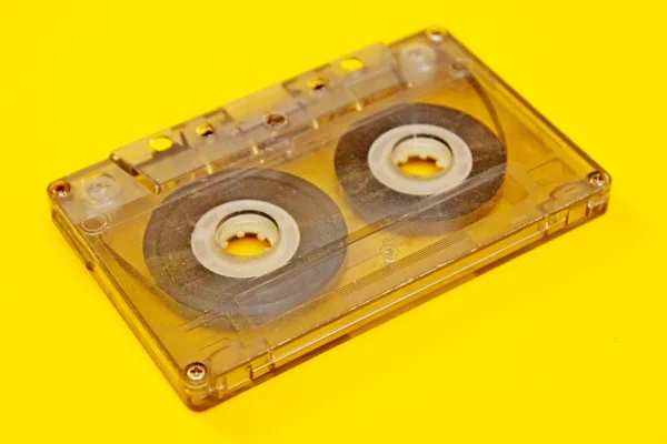 Antiguo casete de audio transparente situado sobre un fondo amarillo —  Fotos de Stock