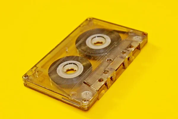 Old transparent audio cassette located on a yellow background Stock Photo