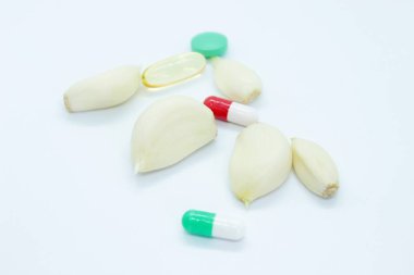 Beyaz arka planda soyulmuş sarımsak ve vitaminler var.