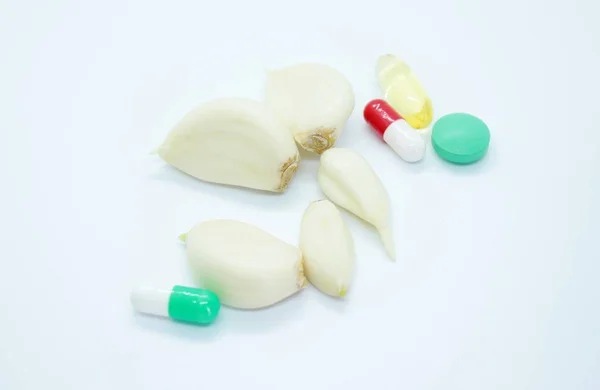 Oloupaný česnek a vitamíny se nacházejí na bílém pozadí — Stock fotografie