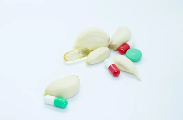 Oloupaný česnek a vitamíny se nacházejí na bílém pozadí — Stock fotografie