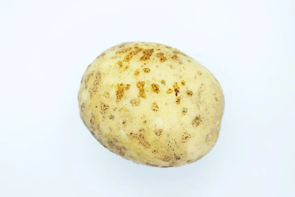 Oskalad potatis ligger på en vit bakgrund — Stockfoto