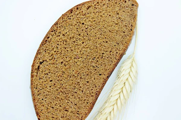 Un morceau de pain et d'épi de seigle situé sur un fond blanc — Photo