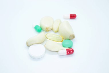 Beyaz arka planda bulunan sarımsak ve vitaminler