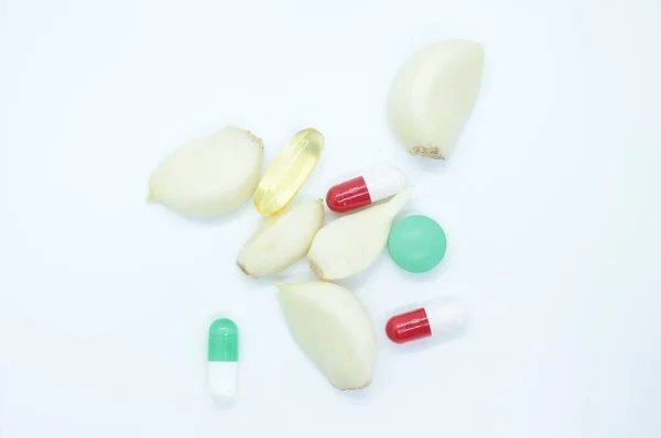 Česnek a vitamíny se nachází na bílém pozadí — Stock fotografie