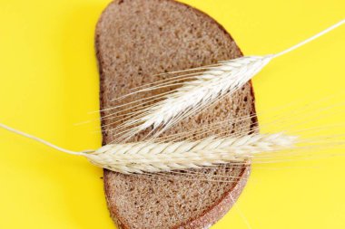 Bir parça çavdar ekmeği ve çavdar ekmeği sarı arka plana konmuş.