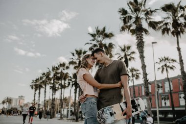 Mutlu genç çift kaykay ile eğleniyor şehrin sokak beach oteller