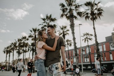 Mutlu genç çift kaykay ile eğleniyor şehrin sokak beach oteller