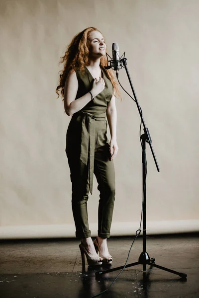 Beautiful singing girl with microphone in studio