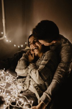 Mutlu çift yatağa siting aşk ve birbirimizi wrappeding çelenk içinde zevk