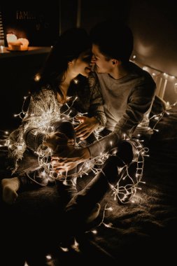 Mutlu çift yatağa siting aşk ve birbirimizi wrappeding çelenk içinde zevk