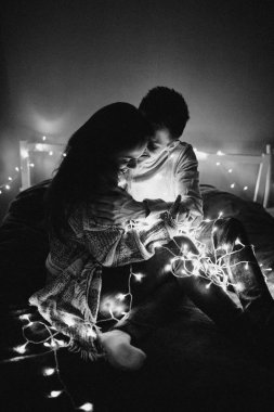 Sevgi dolu çift her diğer yatak odasında çelenk içinde kaydırma yatakta sarıl. Siyah ve beyaz fotoğraf gürültü filtresi ile