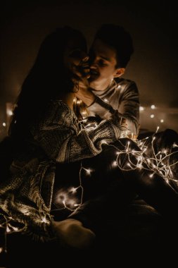 Mutlu çift yatağa siting aşk ve birbirimizi wrappeding çelenk içinde zevk