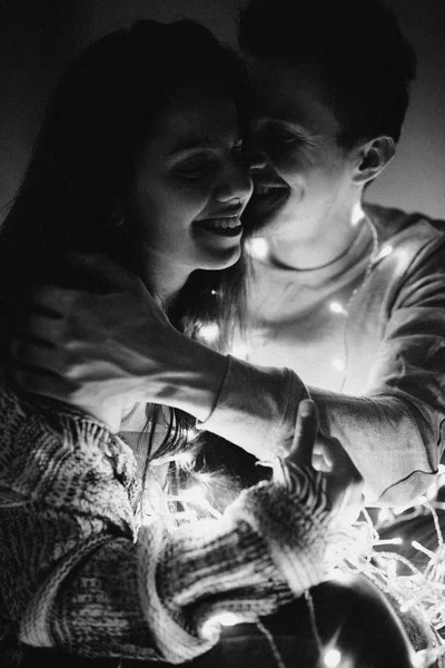 愛情のあるカップルは寝室でガーランドに折り返しのベッドの上に抱き合います ノイズ フィルターと黒と白の写真 — ストック写真