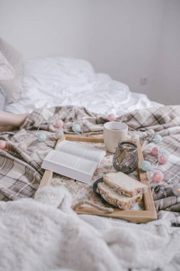 kadın yatakta çay ve kitap ile ahşap tepsi ile