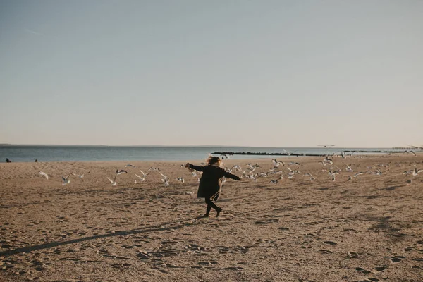 A girl run on the beach with with birds