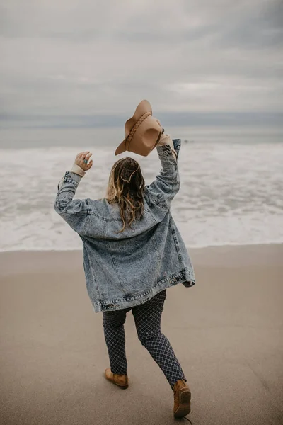 Back view of a woman wearing hat enjoying the view at the ocean
