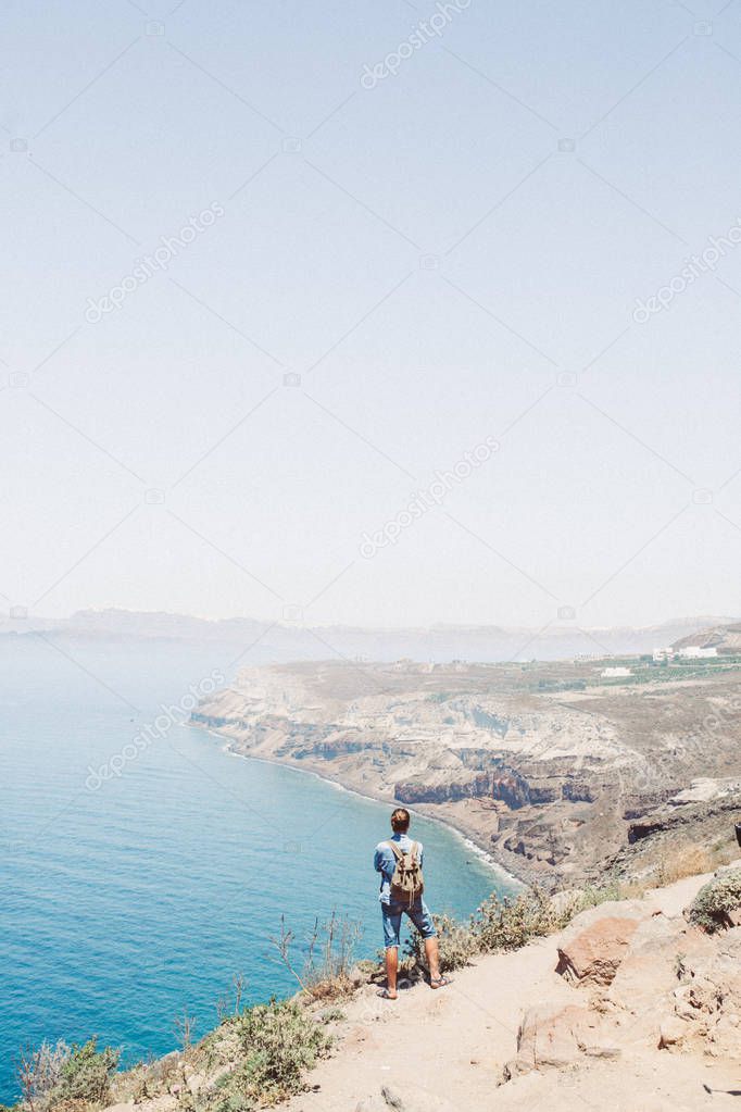 Girl stay at the edge of the cliff and watching to the horizon