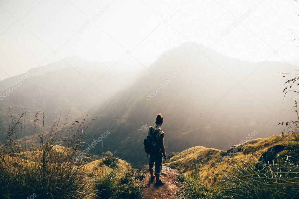 Young man hiking in mountains at sunset and enjoying view of nature
