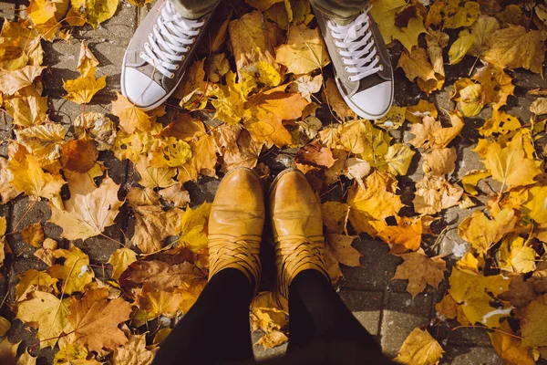 season and people concept - couple\'s feet  with autumn leaves on ground