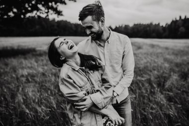 Yürüyüş ve çayırda sarılma aşık genç bir çift. Siyah ve beyaz fotoğraf.