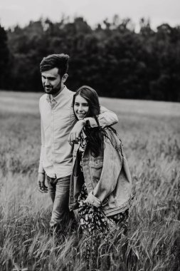 Yürüyüş ve çayırda sarılma aşık genç bir çift. Siyah ve beyaz fotoğraf.