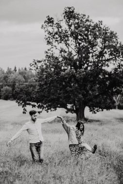 Çayırda yürüyüş aşık genç bir çift. Siyah ve beyaz fotoğraf.