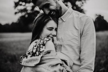 Yürüyüş ve çayırda sarılma aşık genç bir çift. Siyah ve beyaz fotoğraf.