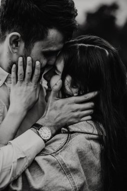 Yürüyüş ve çayırda sarılma aşık genç bir çift. Siyah ve beyaz fotoğraf.