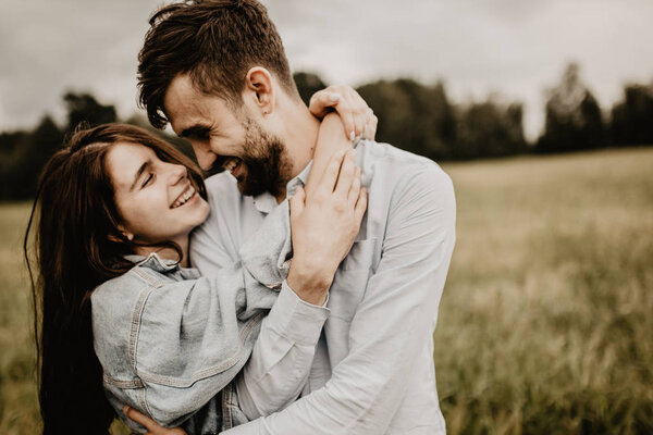 Portrait of young couple in love walking and hugging in the green field