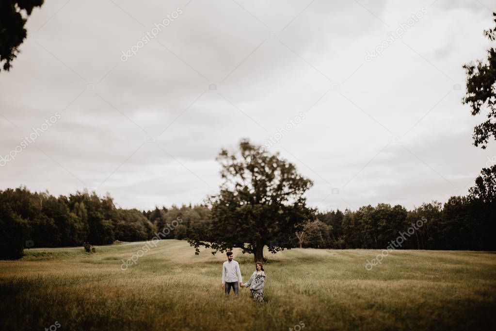 Outdoor shot of young couple walking through meadow hand in hand 