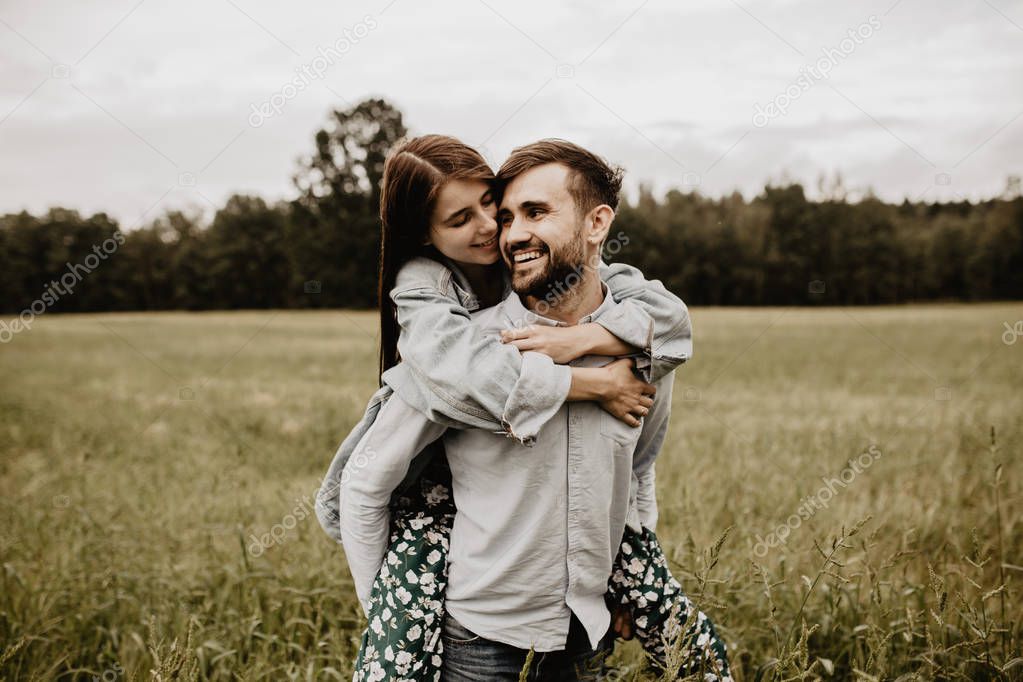 Portrait of young couple in love walking and hugging in the green field