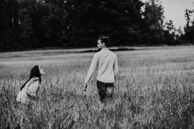 Çayırda yürüyüş aşık genç bir çift. Siyah ve beyaz fotoğraf.