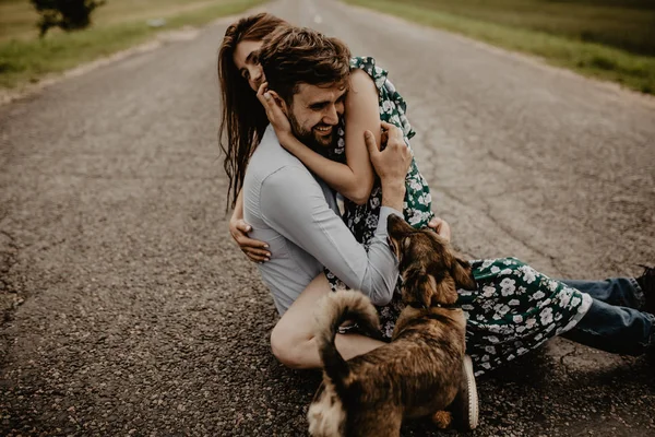 緑の野原で犬を抱いて愛の若いカップルの肖像画 — ストック写真