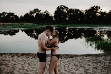 Genç çift sahilde sarılıyor. 