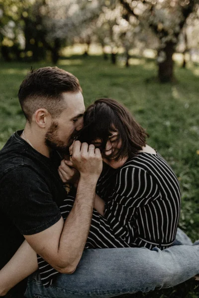 Frühlingsfreunde im blühenden Garten. Junge und Mädchen sitzen auf grünem Gras — Stockfoto